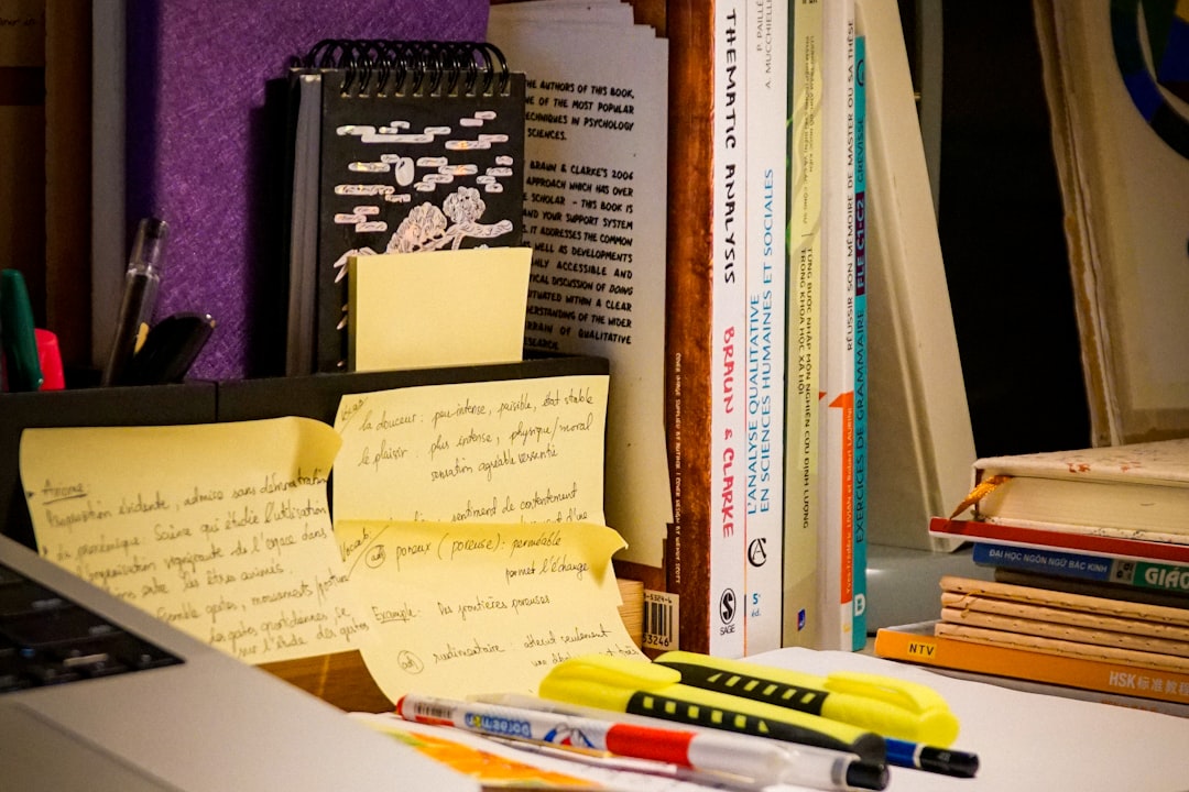 An organised desk with an open book, laptop and study notes